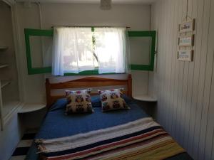 1 dormitorio con cama azul y ventana en La Casita de Monte en Monte Hermoso