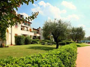 um parque em frente a um edifício com uma árvore em Comfortable apartment with view on swimming pool em Peschiera del Garda