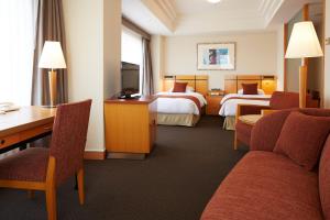 a hotel room with two beds and a desk at JR Hotel Clement Takamatsu in Takamatsu