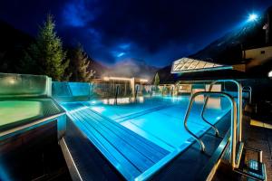 ein Schwimmbad in der Nacht mit eingeschaltetem Licht in der Unterkunft MANNI das Hotel in Mayrhofen