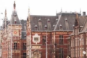 a large red brick building with a clock tower at Hotel Mai Amsterdam in Amsterdam