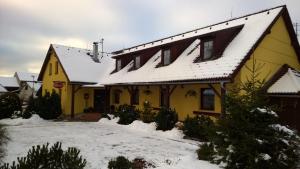 Una casa amarilla con nieve encima. en Penzion Lipno Jantar, en Horní Planá