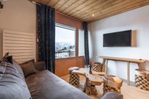 sala de estar con sofá, mesa y TV en Résidence La Forêt du Praz - Courchevel 1850 en Courchevel