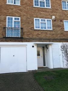 a house with two white garage doors and a brick building at Cozy Homestay in Croydon
