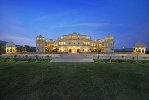 a large white building with its lights on at The Jai Bagh Palace in Jaipur
