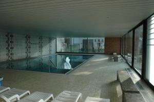 a swimming pool in a building with white chairs at Landgasthof Hirsch in Remshalden