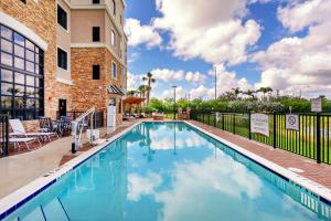 una piscina en un hotel con sillas y un edificio en Staybridge Suites - Fort Lauderdale Airport - West, an IHG Hotel, en Davie