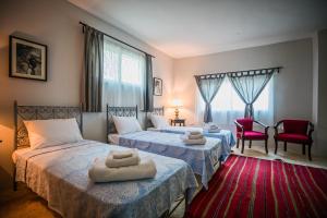 sypialnia z 2 łóżkami i czerwonym dywanem w obiekcie Beit Al Baraka w mieście Um Qeis