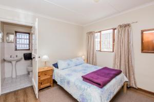 a bedroom with a bed and a bathroom with a sink at Seas the Day in Arniston