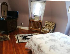 a bedroom with a bed and a chair and a television at Wilson House Bed & Breakfast in Baltimore