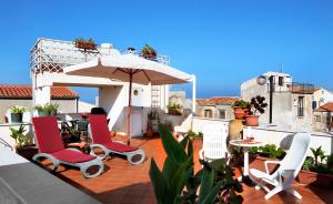 un patio con sillas, una sombrilla y una mesa en Hotel La Giara, en Cefalú