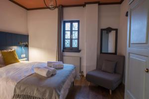 um quarto com uma cama, uma cadeira e uma janela em Charis Guesthouse em Makrinítsa