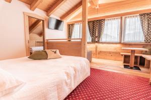 a bedroom with a bed and a table and windows at Hotel Genzianella in Commezzadura