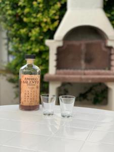 a bottle and two glasses on a table with a bench at Villa Imma in Torre Lapillo