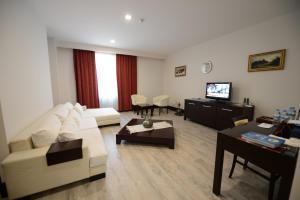 a living room with a white couch and a tv at Arsan Otel in Kahramanmaras