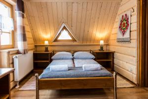 ein Schlafzimmer mit einem Bett in einem Zimmer mit Holzwänden in der Unterkunft udanypobyt Liliowa Chata in Kościelisko