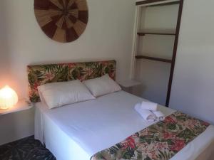 1 dormitorio con 1 cama con sábanas y almohadas blancas en Pousada Minha Casa, en Itacaré