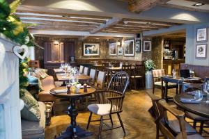 um restaurante com mesas e cadeiras e um bar em The Legh Arms Prestbury em Macclesfield