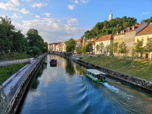 een boot die over een rivier in een stad vaart bij Studio Apartment Gea Tour As Ljubljana in Ljubljana