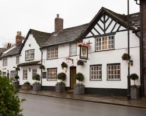 a white building with potted plants on a street at The Legh Arms Prestbury in Macclesfield
