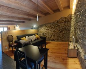 sala de estar con sofá y pared de piedra en Can Rovira de Fogars en Montseny