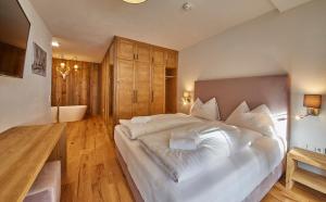 a bedroom with a large white bed and wooden floors at Residenz Der Wieshofer in Saalbach-Hinterglemm