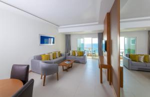 Ramada by Wyndham Beach Hotel Ajman في عجمان: غرفة معيشة بها كنب وكراسي وطاولة