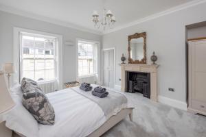 a white bedroom with a bed and a fireplace at Brunswick Place in Bath