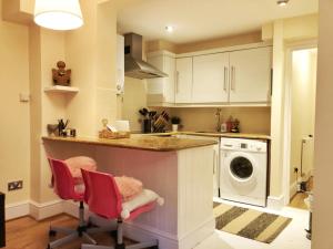 a kitchen with white cabinets and a washer and dryer at Lovely flat in West Kensington Central London in London