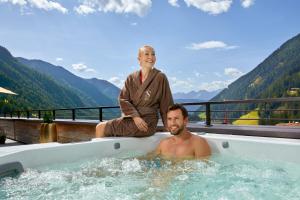 a woman sitting on the edge of a bath tub with a man at Chalet SALENA luxury lodge in Santa Maddalena in Casies