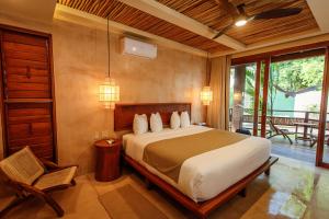 a bedroom with a large bed and a balcony at Hotel Carolina Bacalar in Bacalar