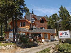 une maison en rondins avec un panneau devant elle dans l'établissement HTL La Malinka, à San Carlos de Bariloche