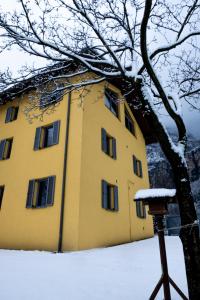 un edificio amarillo con nieve en el suelo en Agriturismo La Casa Gialla, en Romagnano