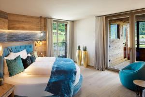 a bedroom with a large bed and a blue chair at Chalet SALENA luxury lodge in Santa Maddalena