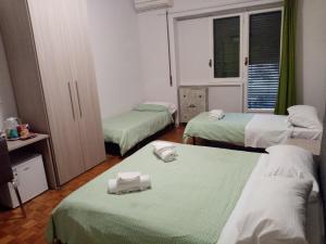 ローマにあるOlimpica Relais guest house CIR 28624のベッド3台(緑と白のシーツ付)が備わるお部屋