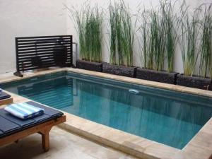 a swimming pool with a bench and plants at Villa Indah Kuta Royal - Private Pool - Optic Fiber High Speed Internet in Kuta