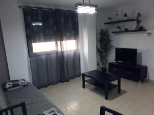 Sala de estar con cama, mesa y TV en Apartamento Eursu Playa, en Málaga
