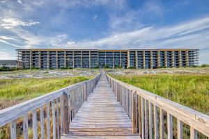 uma ponte de madeira que leva a um edifício na praia em Holiday Isle em Dauphin Island