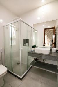 a bathroom with a glass shower and a sink at Pousada do Frei in Búzios