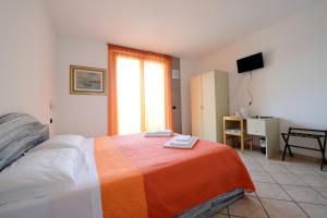 a bedroom with a bed with an orange and white blanket at Albergo Navene in Malcesine