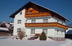 a large white building with a wooden roof in the snow at Schusterbauernhof in Bad Mitterndorf