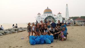 a group of people posing for a picture on the beach at Ringo's Foyer in Melaka