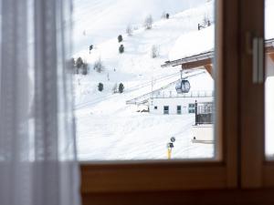 een raam met uitzicht op een besneeuwde helling bij Glanzer Homes Hochsölden in Sölden