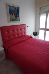 a red bed with a red comforter in a bedroom at Hotel Diga in Marina di Ravenna