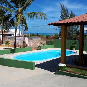 a swimming pool with a gazebo and the ocean at Pousada O Tabuleiro in Jacumã
