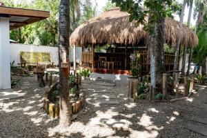 un edificio con una capanna di paglia con palme di Crazy Bears Hostel a Moalboal