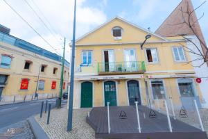 un edificio giallo con porte verdi su una strada cittadina di SwissLisbon Guest House a Lisbona
