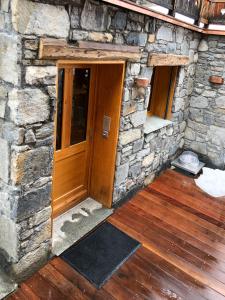 um edifício de pedra com uma porta de madeira e pisos de madeira em Magnifique Appartement neuf de 60m2 Méribel centre em Les Allues