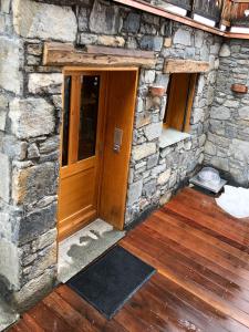 a stone building with a wooden door and wooden floors at Magnifique Appartement neuf de 60m2 Méribel centre in Les Allues