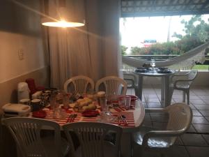 a dining room table with chairs and a table with food on it at Apart-Hotel Beira Mar em Mar Grande - Vera Cruz - Ilha de Itaparica in Aratuba Beach